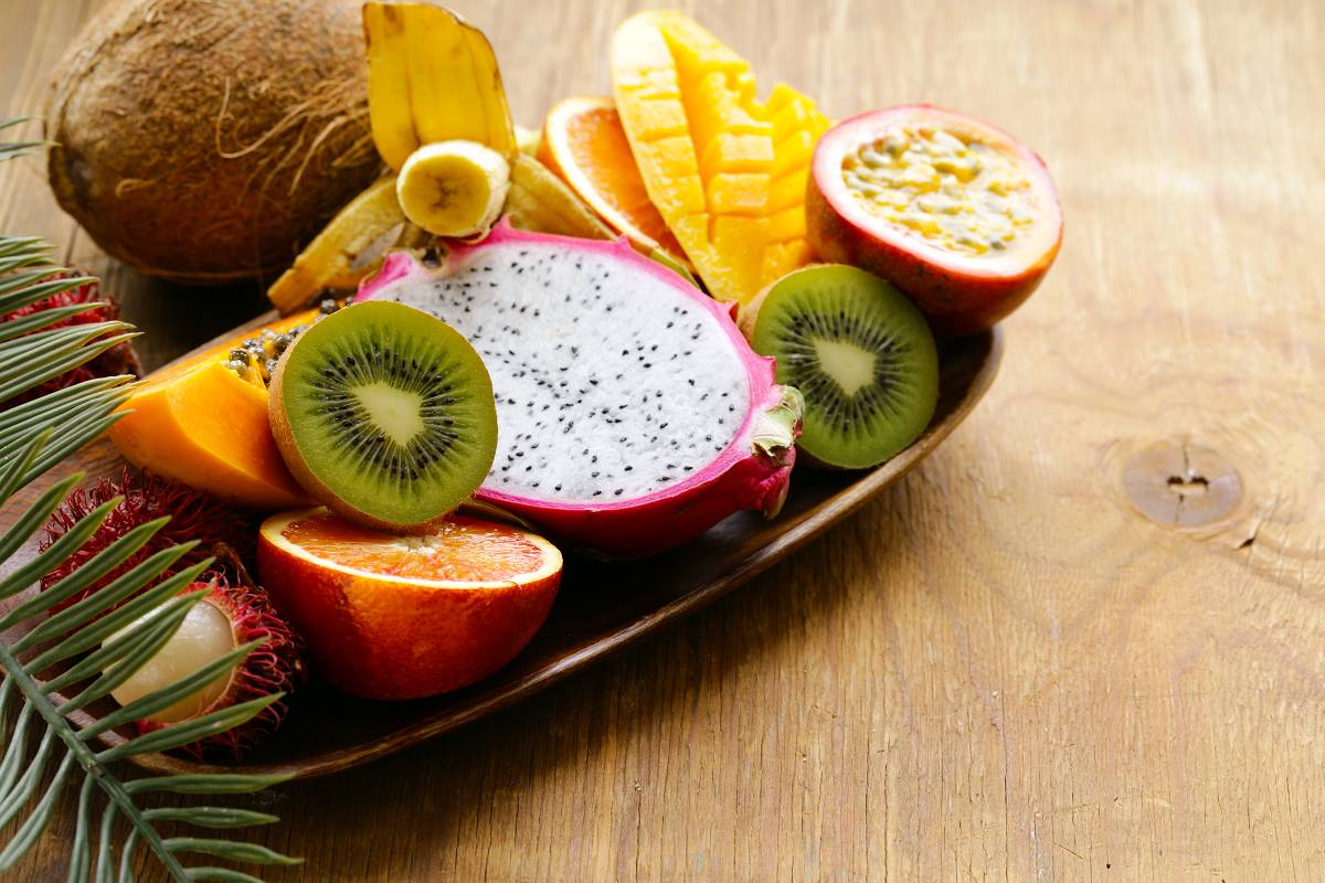 A collection of tropical fruits are cut and being served